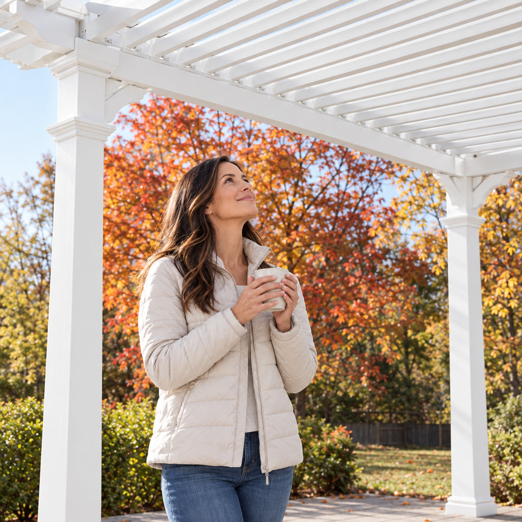 Vinyl Pergola Designed, a woman in a light jacket tilting her face upward toward the louvers with a satisfied expression